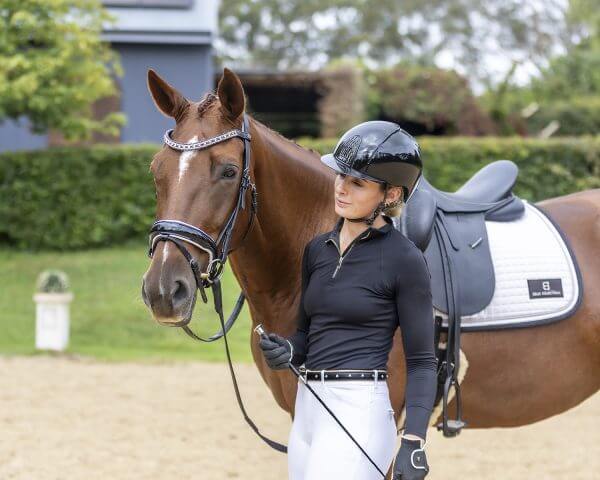 Rider standing next to horse in arena